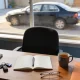 A home desk with an open notebook of blank pages, a pen, car keys, glasses and a mug of tea, with a car parked in the driveway beyond the window
