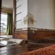 A blistered, water-stained patch of paint above a timber skirting in an older Australian home, with a scraper and drop sheet on the floorboards