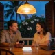 A couple talking at a timber table on a Queenslander verandah at dusk under a pendant light, with a phone, a stack of blank paper, a closed laptop and two glasses of water, and frangipani and palms outside